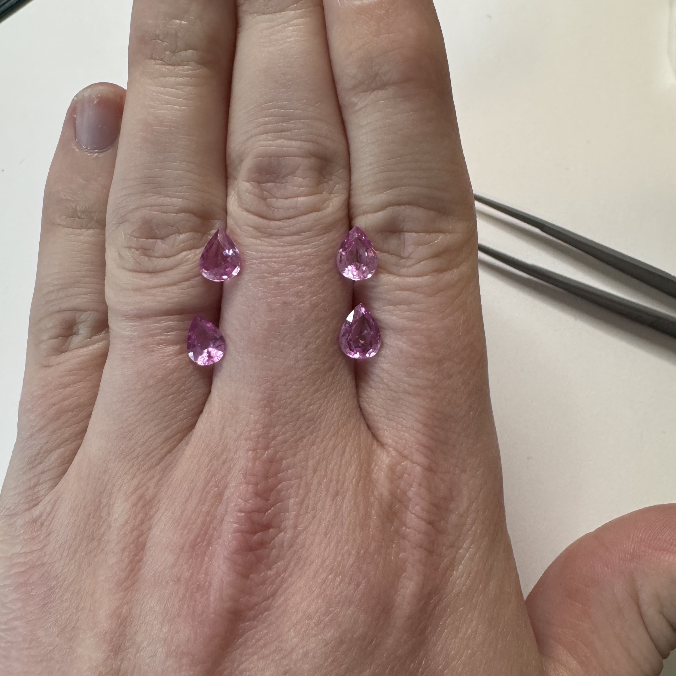 Picture of a hand with 4 pink pear sapphires