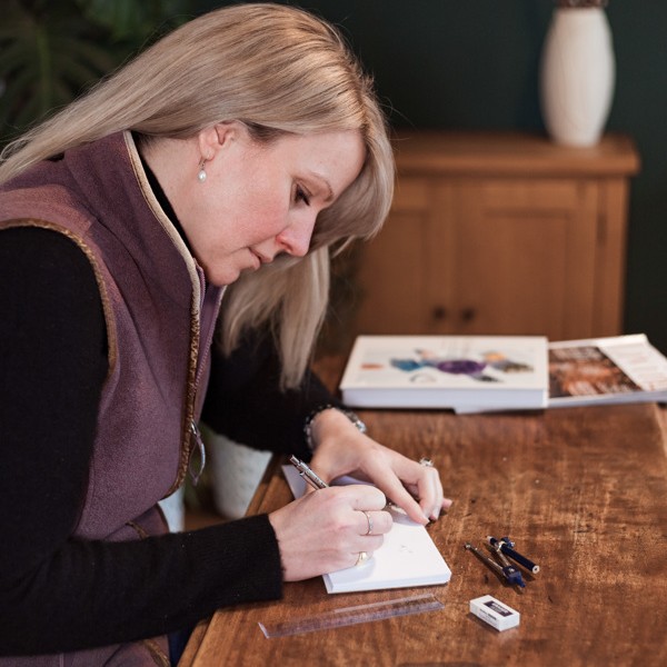 Blonde woman writing at a wooden desk